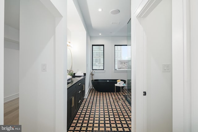 bathroom featuring vanity, hardwood / wood-style flooring, and a tub