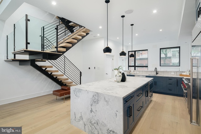 kitchen featuring sink, light hardwood / wood-style flooring, a kitchen island, and hanging light fixtures