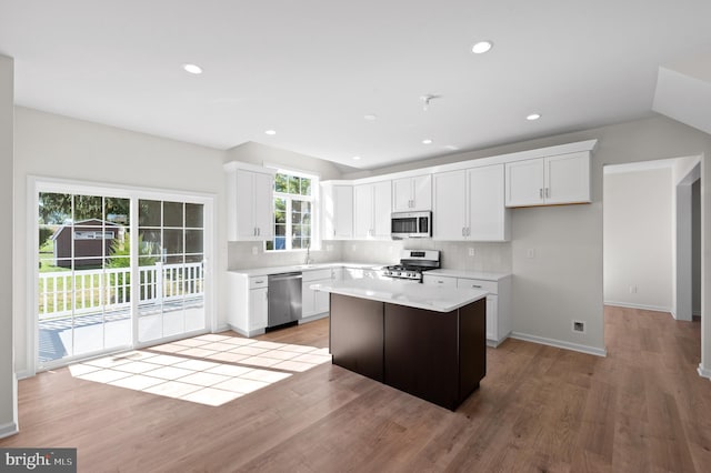 kitchen with light hardwood / wood-style flooring, white cabinets, stainless steel appliances, and a kitchen island