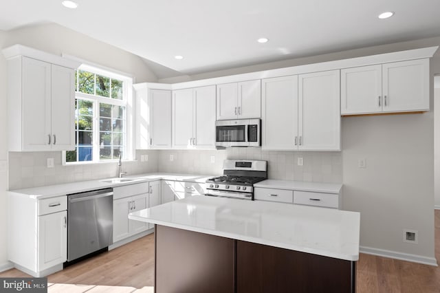 kitchen featuring decorative backsplash, appliances with stainless steel finishes, light wood-type flooring, and white cabinets