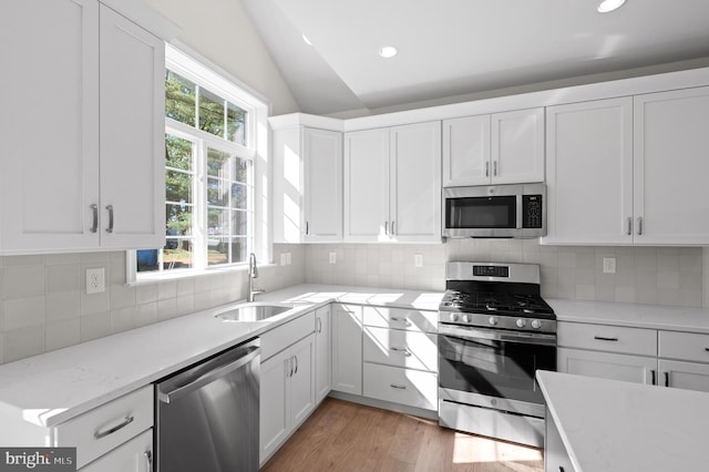 kitchen featuring sink, a healthy amount of sunlight, appliances with stainless steel finishes, and lofted ceiling