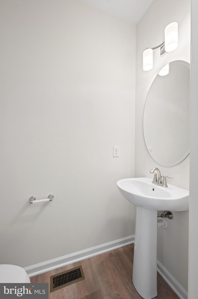 bathroom featuring toilet, sink, and hardwood / wood-style floors