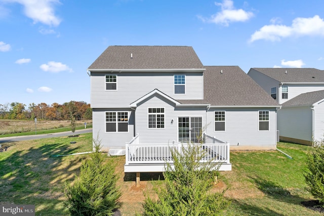 rear view of house featuring a wooden deck and a lawn