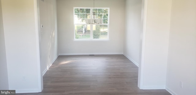 unfurnished room featuring a notable chandelier, a wealth of natural light, and hardwood / wood-style floors