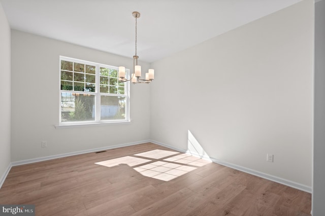 unfurnished room with light hardwood / wood-style flooring and an inviting chandelier