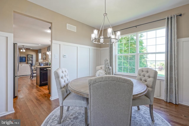 dining area with wood-type flooring and ceiling fan with notable chandelier