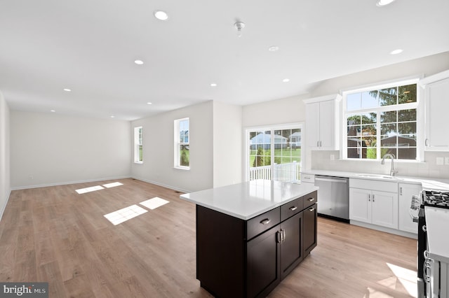 kitchen with backsplash, stainless steel dishwasher, light wood-type flooring, gas range, and a center island