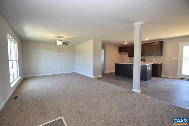 unfurnished living room featuring sink, dark wood-type flooring, decorative columns, and ceiling fan