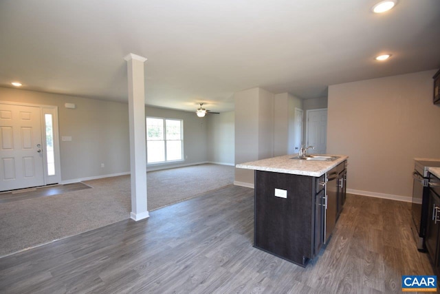 kitchen featuring a kitchen island with sink, dark wood-type flooring, sink, decorative columns, and ceiling fan