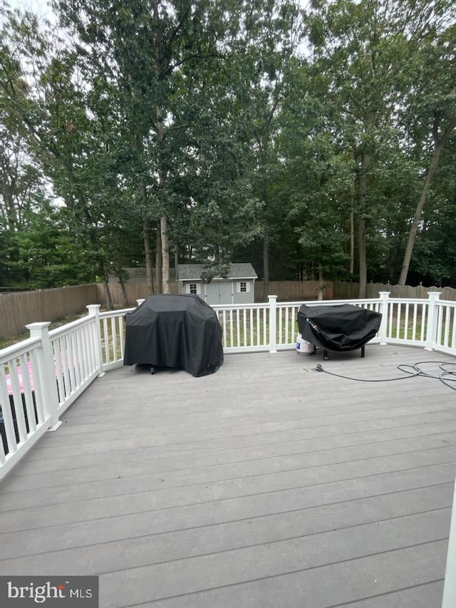 wooden terrace featuring a shed and area for grilling