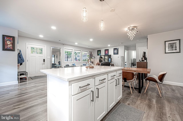 kitchen featuring a kitchen island, pendant lighting, white cabinetry, light stone counters, and light hardwood / wood-style floors