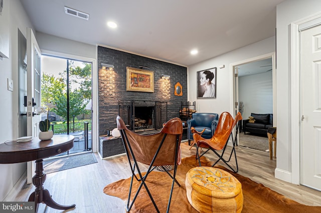 living room featuring a brick fireplace, wood finished floors, visible vents, and recessed lighting