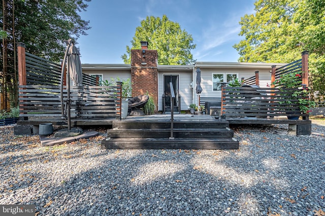 rear view of house with a wooden deck and a chimney
