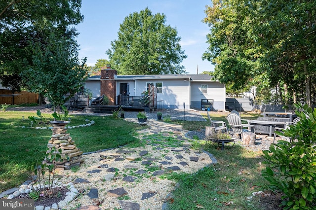 back of house with fence, an outdoor fire pit, a yard, and a deck
