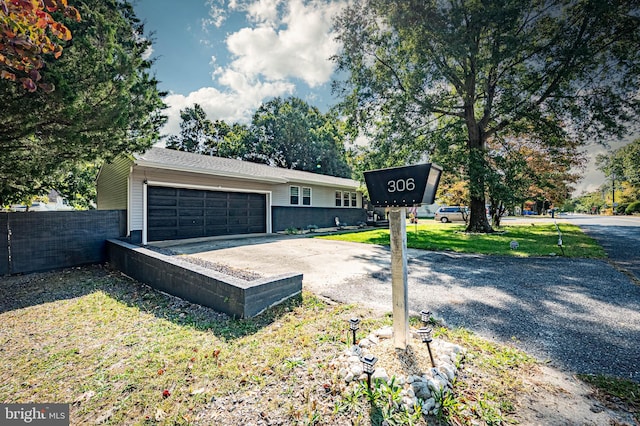 exterior space featuring fence, a front yard, driveway, and a garage