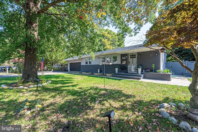exterior space featuring fence, brick siding, a front yard, and a garage