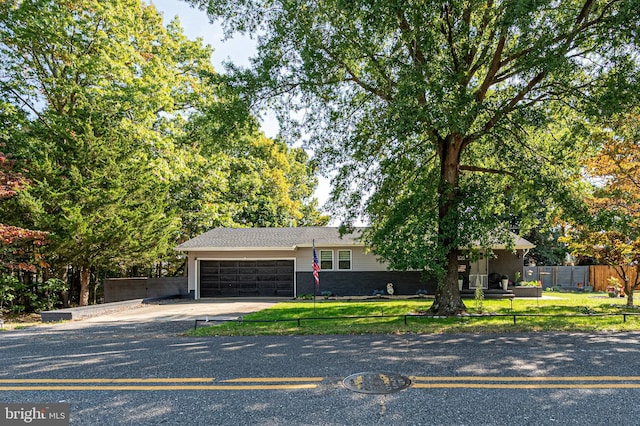 view of front of house with fence, an attached garage, a front lawn, and concrete driveway