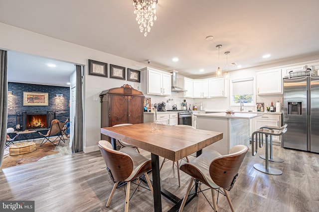 dining space with a fireplace, recessed lighting, and light wood-type flooring