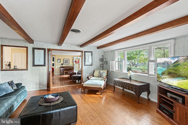 living room featuring wooden walls, hardwood / wood-style flooring, and beam ceiling