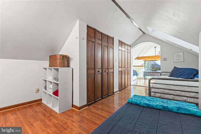 bedroom with wood-type flooring and vaulted ceiling with skylight