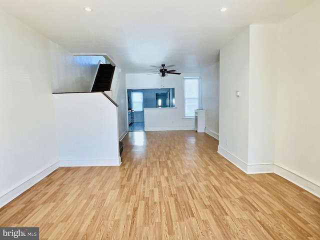 unfurnished living room featuring light hardwood / wood-style floors, radiator, and ceiling fan