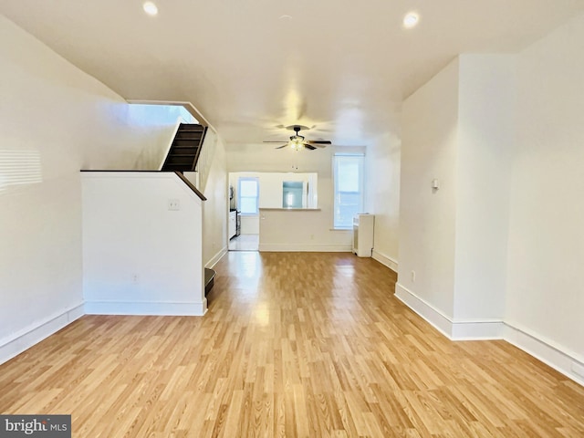 unfurnished living room with radiator heating unit, light wood-type flooring, and ceiling fan