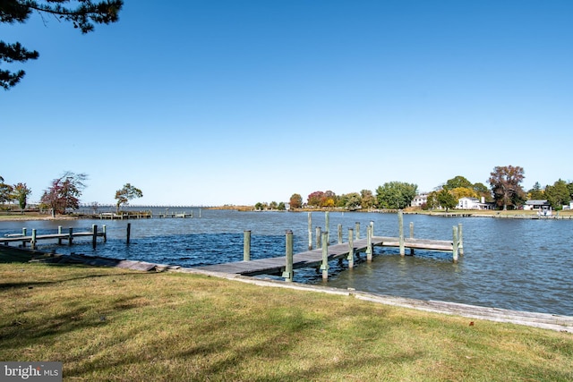 view of dock with a lawn and a water view