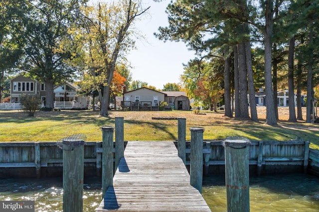 view of dock with a lawn and a water view