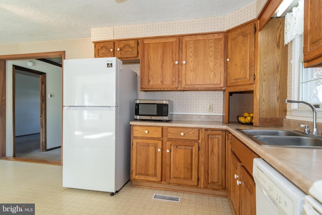 kitchen with sink, a textured ceiling, and white appliances