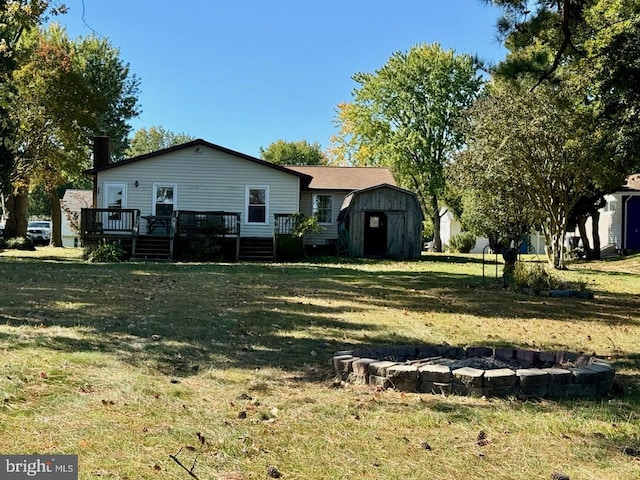 back of property with a yard, a deck, and a storage unit