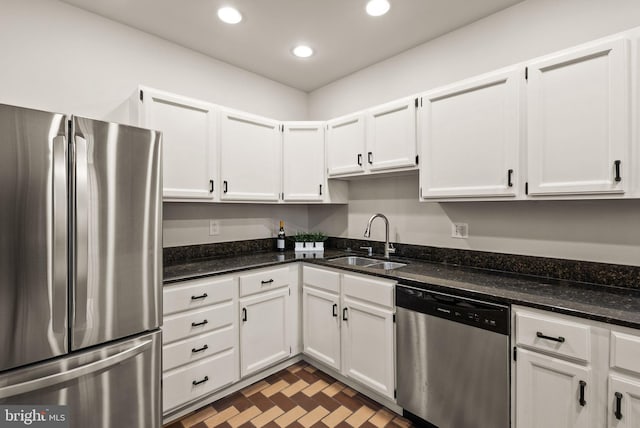 kitchen with white cabinetry, dark stone countertops, appliances with stainless steel finishes, and sink