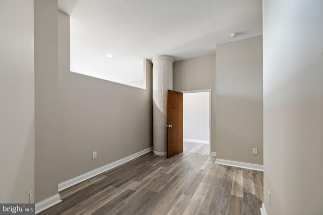 spare room featuring hardwood / wood-style floors and decorative columns