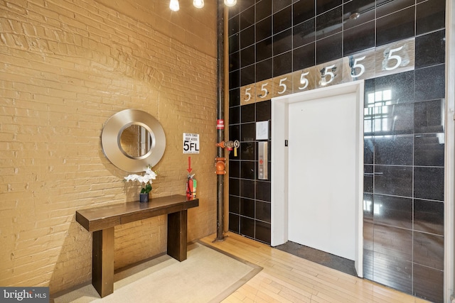 entrance foyer with wood-type flooring and brick wall