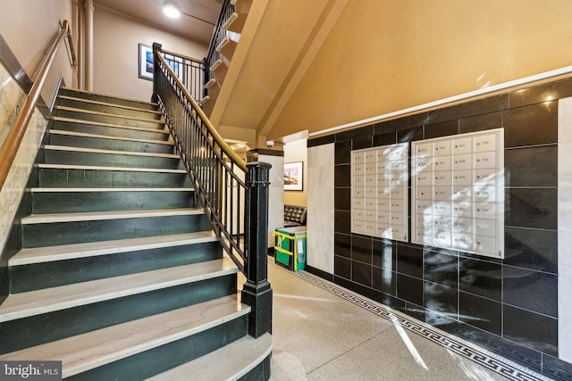 stairs featuring tile walls, a high ceiling, and mail boxes