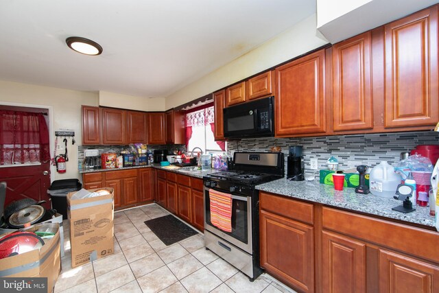 kitchen featuring gas stove, light tile patterned flooring, sink, and backsplash