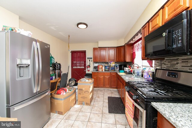 kitchen with light stone countertops, sink, stainless steel appliances, decorative backsplash, and light tile patterned floors