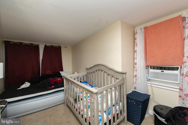 bedroom with cooling unit, light colored carpet, and a crib