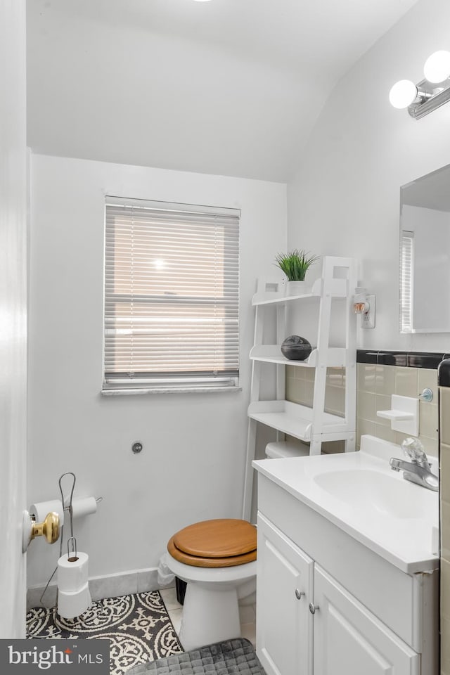 bathroom with toilet, vanity, tile patterned floors, and vaulted ceiling