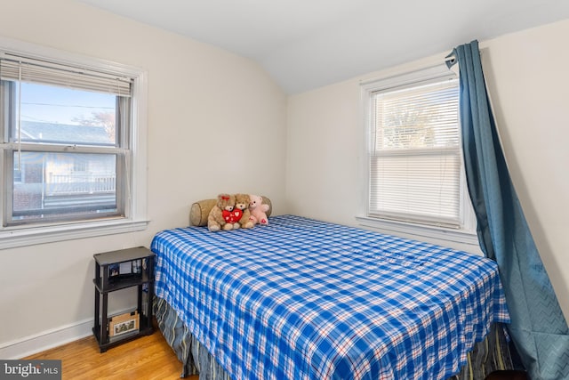 bedroom with hardwood / wood-style flooring, multiple windows, and vaulted ceiling