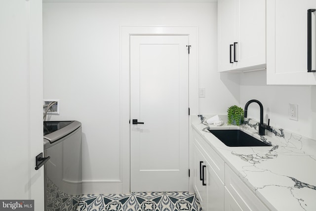 washroom with cabinets, hookup for a washing machine, sink, and tile patterned flooring