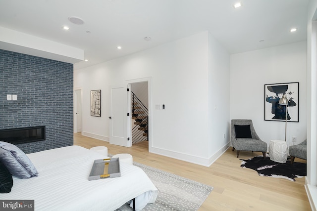 bedroom with a spacious closet, a fireplace, and light hardwood / wood-style floors