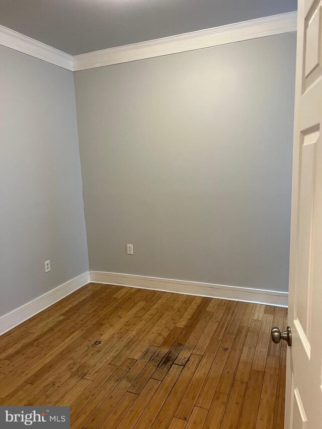 empty room featuring crown molding and hardwood / wood-style floors