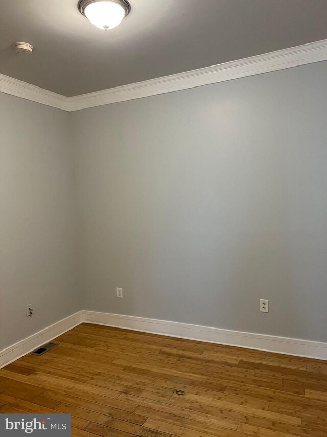 spare room with ornamental molding and hardwood / wood-style flooring