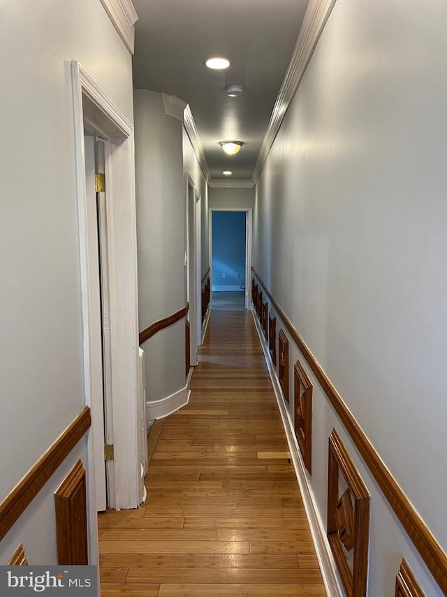 corridor with ornamental molding and light wood-type flooring