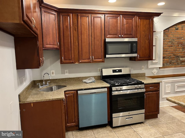 kitchen with stainless steel appliances, sink, light stone counters, and light tile patterned floors