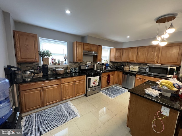 kitchen with light tile patterned floors, appliances with stainless steel finishes, backsplash, dark stone countertops, and pendant lighting