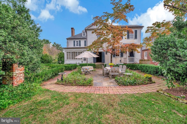 back of house featuring a patio, a lawn, and a sunroom