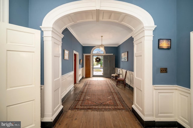 hallway featuring decorative columns, ornamental molding, and dark hardwood / wood-style flooring