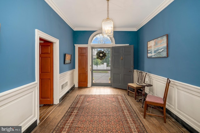 foyer entrance with a notable chandelier, ornamental molding, and hardwood / wood-style flooring