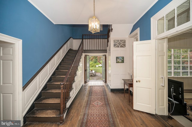 entryway featuring an inviting chandelier, ornamental molding, dark hardwood / wood-style floors, and a healthy amount of sunlight